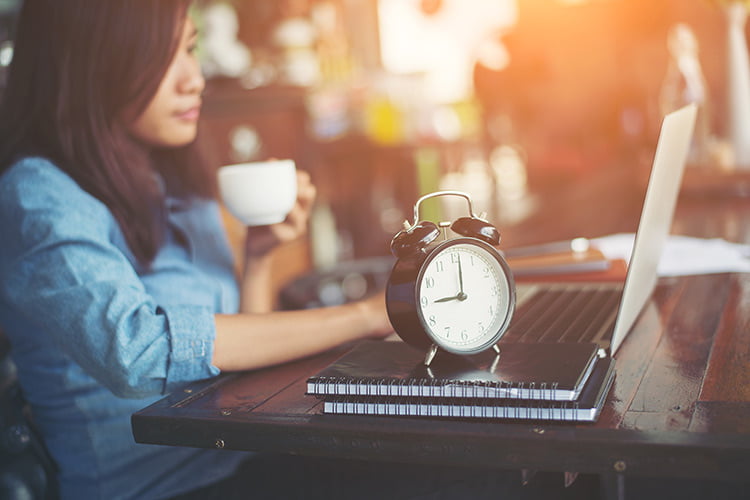 picture shows woman on laptop with clock