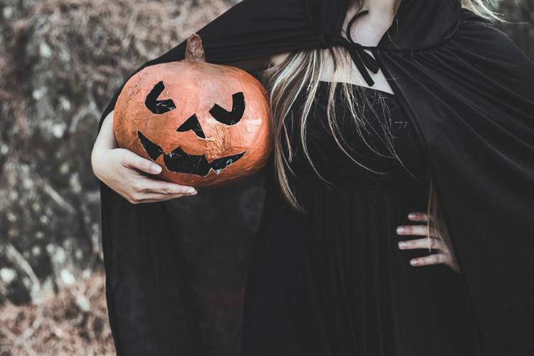 a witch wears a pumpkin as a Halloween Costume