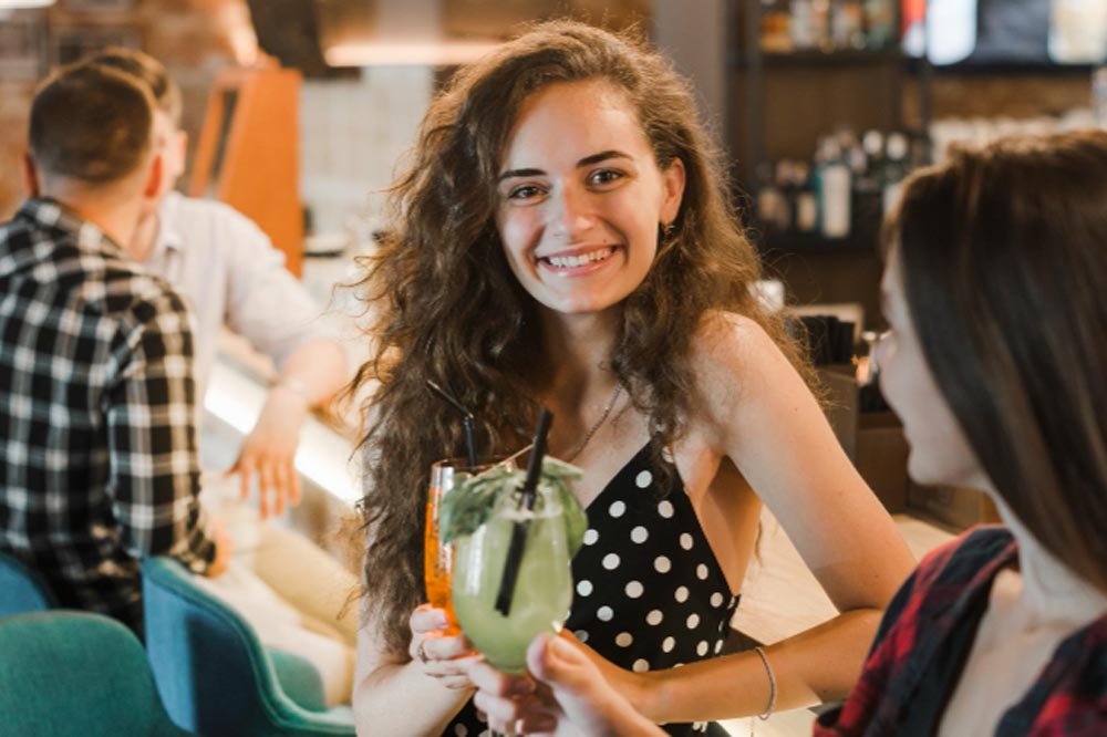 junge Frau an der Bar mit Cocktail in der Hand