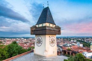 Schlossberg Graz im Sonnenuntergang mit Regenwolken
